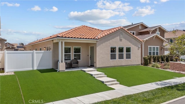 mediterranean / spanish house with stucco siding, a tile roof, a patio, fence, and a front yard