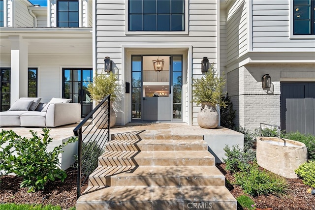 view of exterior entry featuring brick siding and covered porch