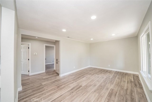 empty room featuring recessed lighting, baseboards, and light wood-style floors