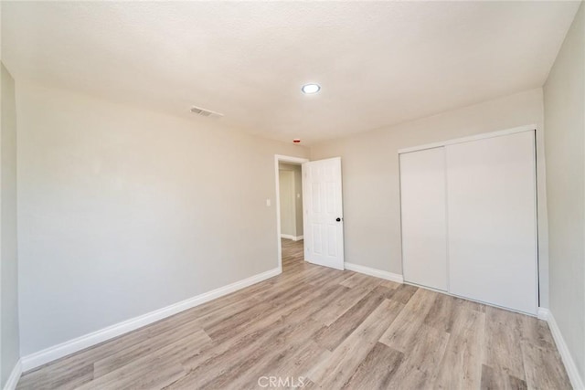 unfurnished bedroom with light wood-style floors, a closet, and baseboards