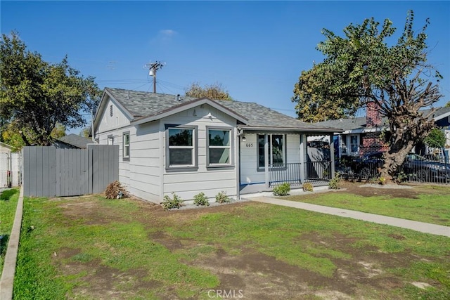 bungalow with covered porch, a front lawn, and fence