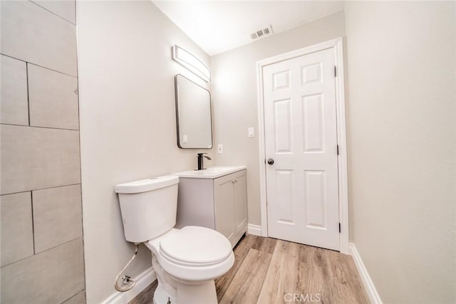 bathroom featuring vanity, wood finished floors, visible vents, baseboards, and toilet