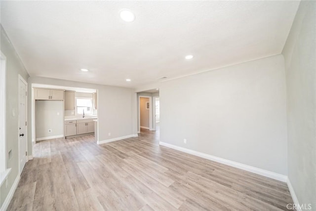 unfurnished living room with recessed lighting, light wood-style flooring, and baseboards