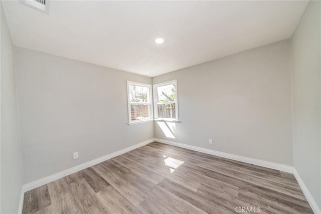 spare room featuring visible vents, recessed lighting, wood finished floors, and baseboards