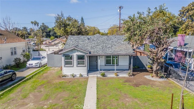 view of front of house featuring a porch, fence, and a front lawn