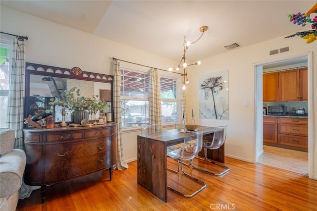 dining space featuring a chandelier, visible vents, light wood-style flooring, and baseboards