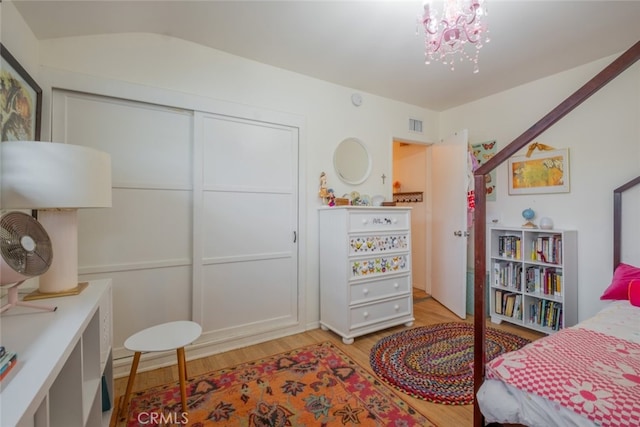 bedroom with an inviting chandelier, light wood-style floors, visible vents, and a closet