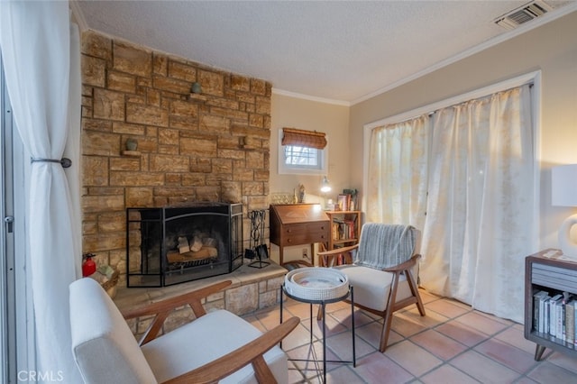 living area featuring tile patterned floors, visible vents, ornamental molding, a textured ceiling, and a fireplace