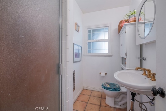 bathroom featuring baseboards, a sink, an enclosed shower, tile patterned floors, and toilet