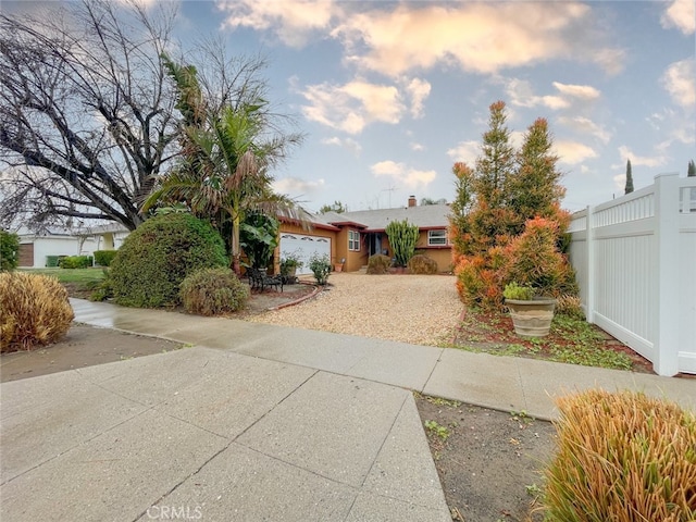 view of front facade with concrete driveway, an attached garage, and fence