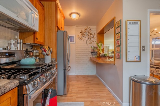 kitchen featuring brown cabinetry, backsplash, light wood finished floors, and stainless steel appliances