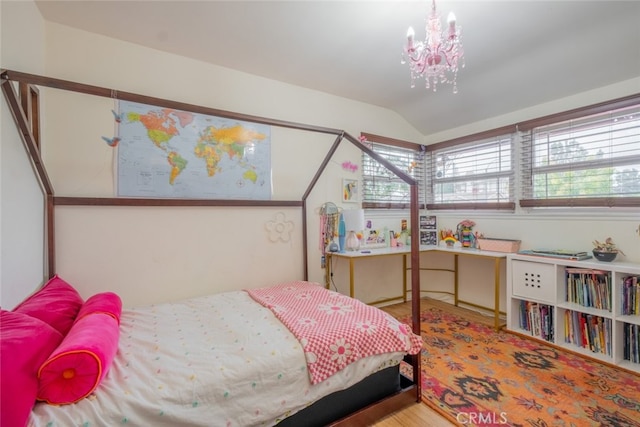 bedroom featuring lofted ceiling, wood finished floors, and a chandelier