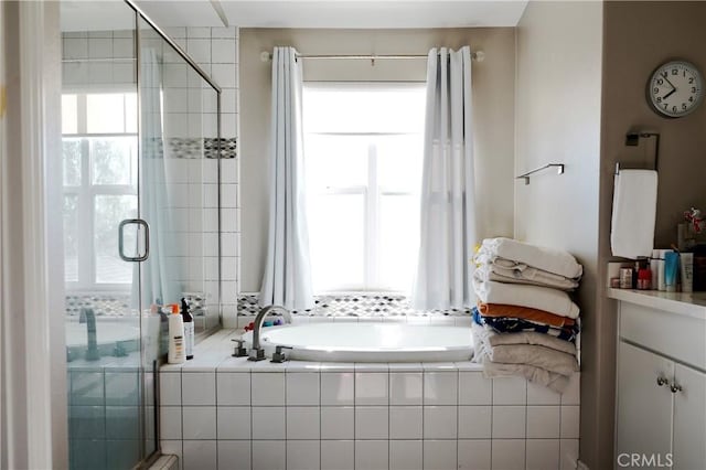 full bathroom featuring vanity, a garden tub, and a shower stall