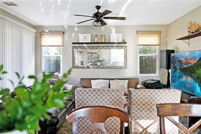 living area featuring visible vents, a healthy amount of sunlight, and a ceiling fan