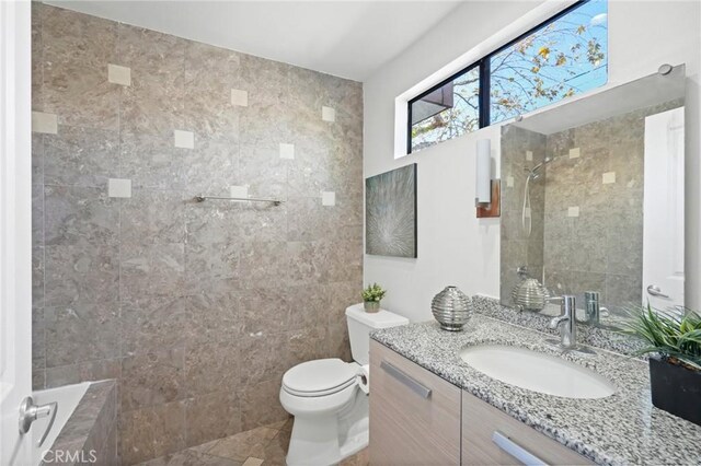 bathroom featuring tiled shower, toilet, and vanity