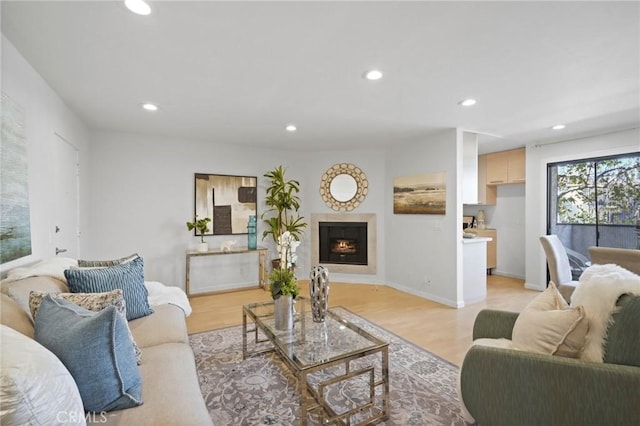 living area featuring recessed lighting, baseboards, a lit fireplace, and light wood-style flooring