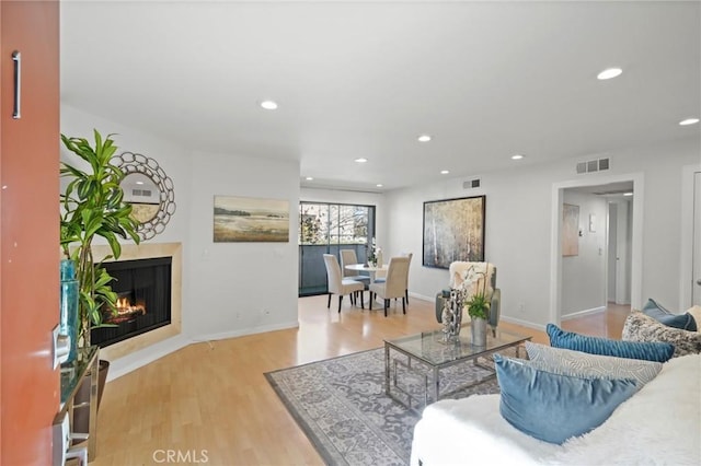 living area with visible vents, recessed lighting, light wood-type flooring, and a fireplace with flush hearth