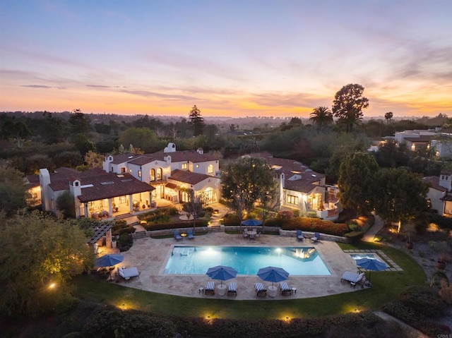 pool at dusk featuring a patio area and an outdoor pool