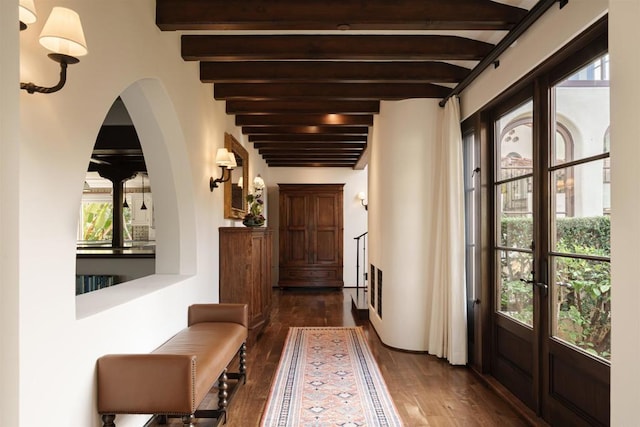 doorway to outside with dark wood-type flooring and beamed ceiling