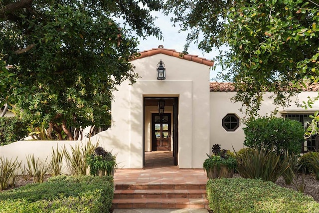 view of exterior entry with a tile roof and stucco siding