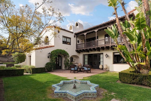 back of house with a yard, a patio, a balcony, and stucco siding