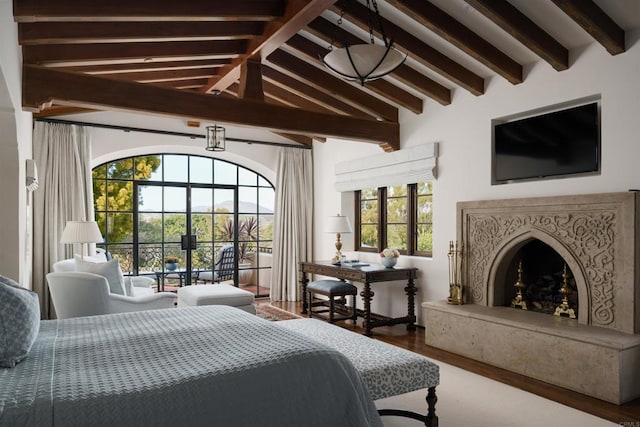 bedroom with wood finished floors, vaulted ceiling with beams, and a fireplace