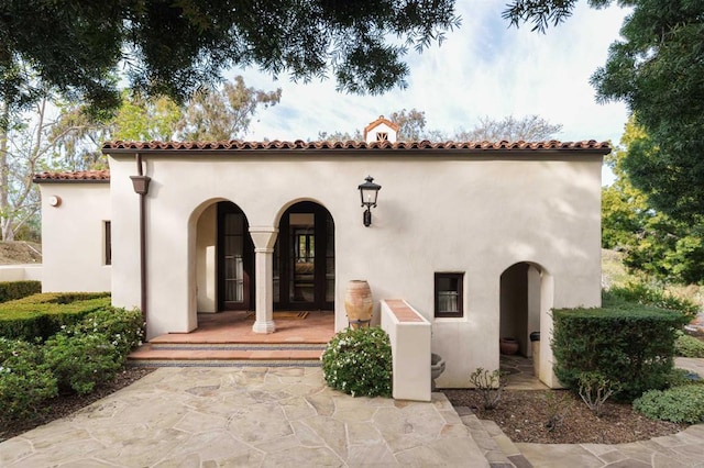 exterior space featuring a porch, a tiled roof, and stucco siding