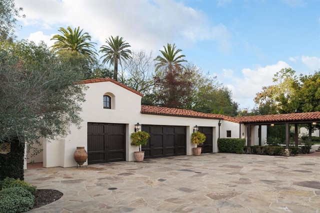 view of front of house with a tiled roof, a garage, driveway, and stucco siding