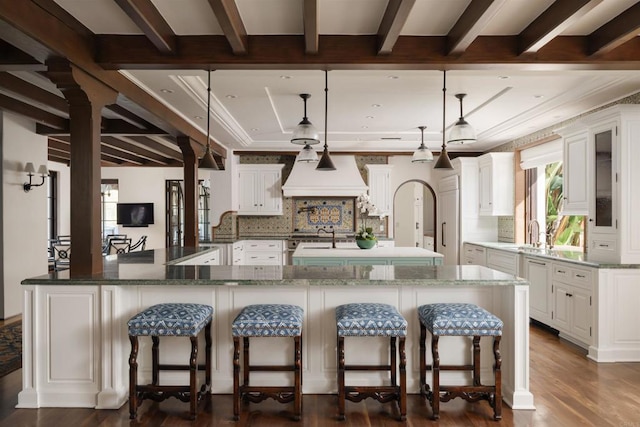 kitchen featuring beam ceiling, a large island, a breakfast bar, and custom range hood