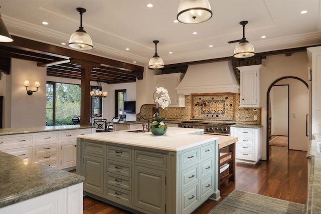 kitchen featuring a center island with sink, white cabinets, and custom range hood