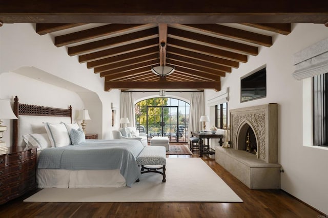 bedroom with lofted ceiling with beams, wood finished floors, and a high end fireplace