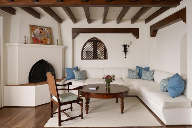 living room featuring wood finished floors, beamed ceiling, a fireplace, and arched walkways