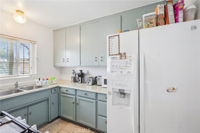 kitchen with a sink, white fridge with ice dispenser, light wood-style flooring, and light countertops