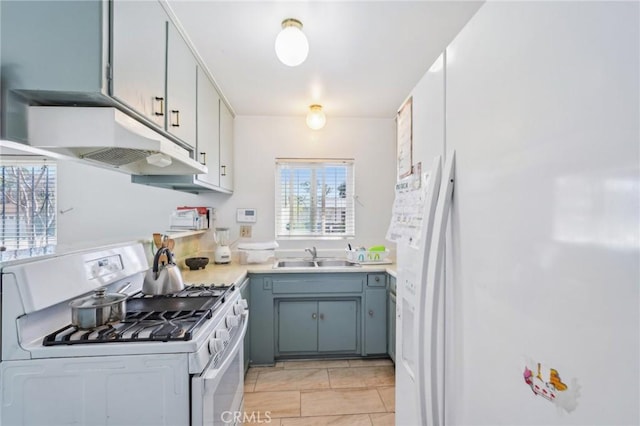 kitchen with under cabinet range hood, white appliances, light countertops, and a sink