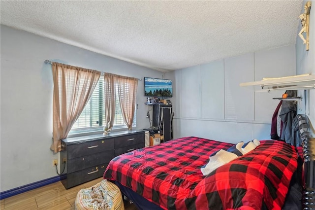 bedroom with light wood-style flooring, baseboards, and a textured ceiling