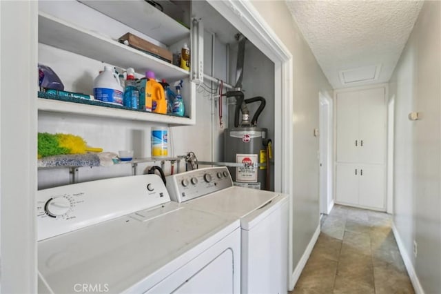 clothes washing area featuring a textured ceiling, water heater, light tile patterned floors, attic access, and washing machine and clothes dryer