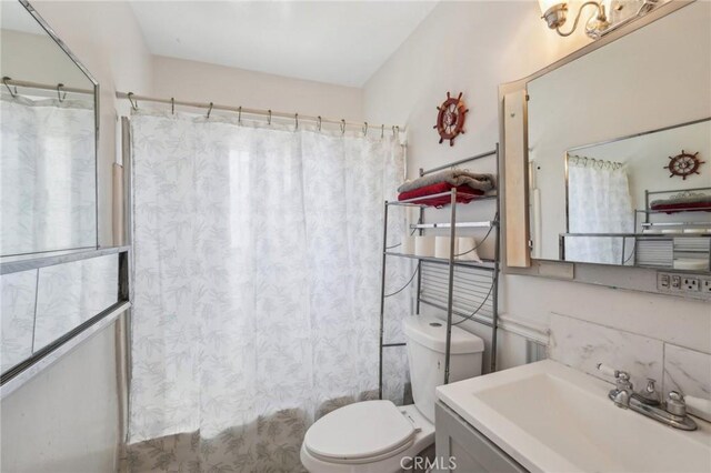 bathroom featuring vanity, shower / tub combo, and toilet