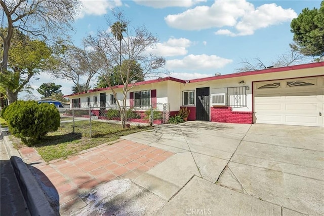 ranch-style home featuring brick siding, fence, concrete driveway, stucco siding, and a garage