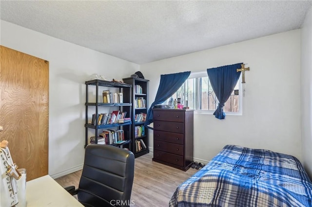 bedroom featuring baseboards, a textured ceiling, and wood finished floors