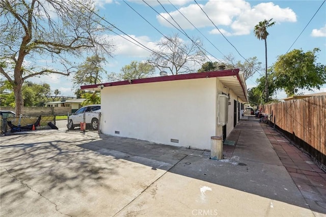 view of side of home featuring crawl space, stucco siding, and fence