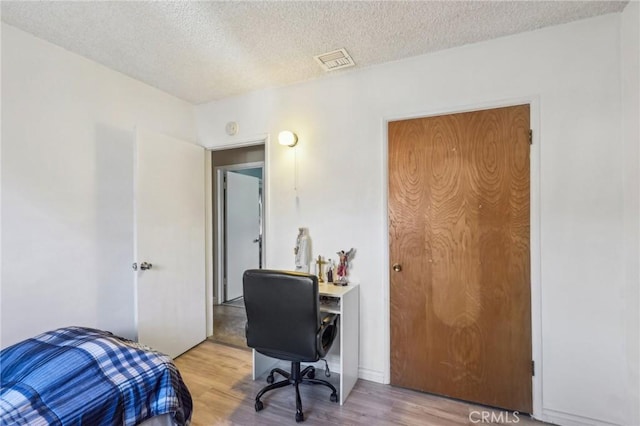 office space with visible vents, light wood finished floors, and a textured ceiling