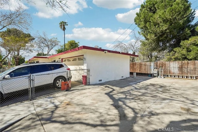 view of home's exterior with stucco siding, a garage, fence, concrete driveway, and crawl space