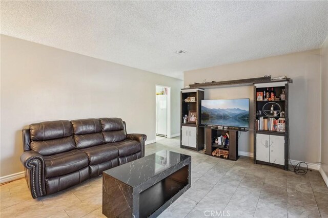 living area with a textured ceiling and baseboards