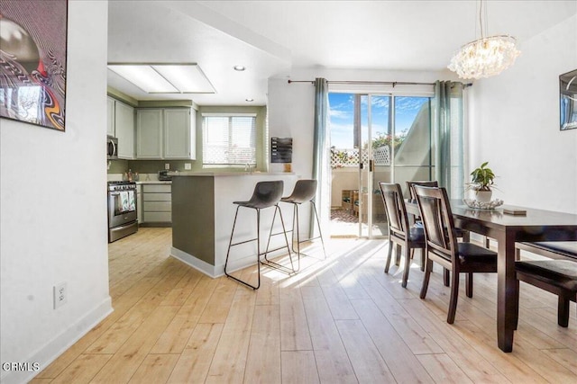 kitchen featuring green cabinets, light wood-type flooring, a kitchen breakfast bar, appliances with stainless steel finishes, and a peninsula