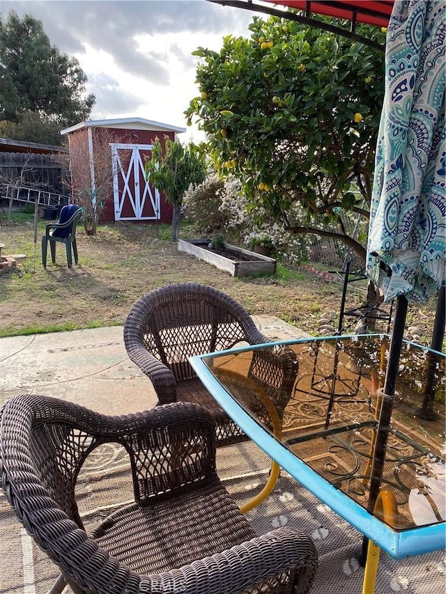 view of patio with an outbuilding, a storage unit, and fence