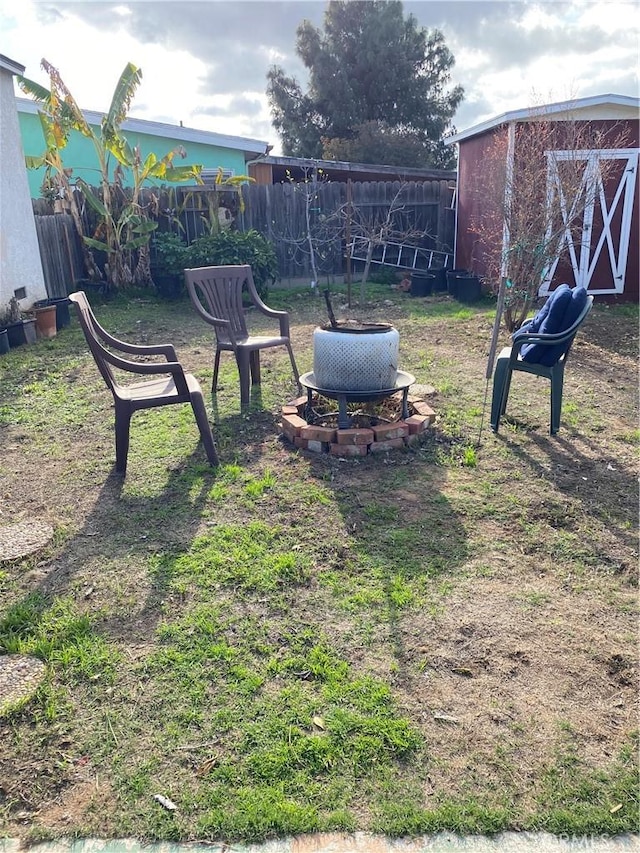 view of yard with an outbuilding, fence, and an outdoor fire pit