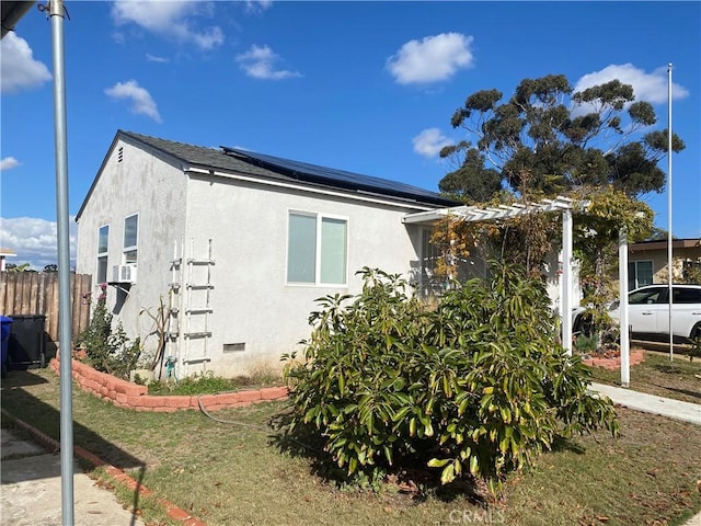 view of side of property featuring crawl space, solar panels, fence, and stucco siding