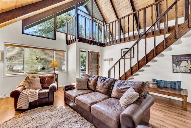 living room featuring wood finished floors, baseboards, beam ceiling, stairs, and wood ceiling