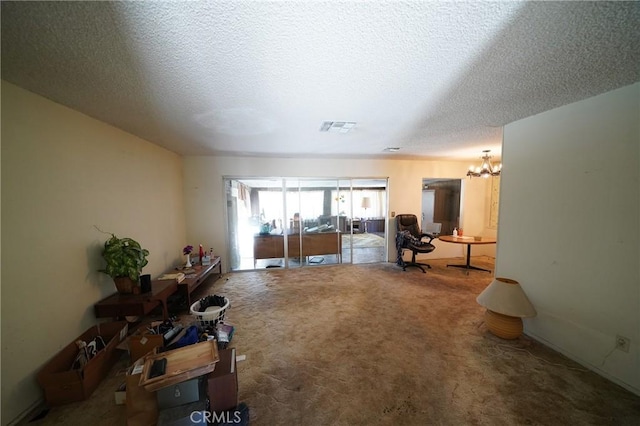 carpeted living area featuring a notable chandelier, visible vents, and a textured ceiling