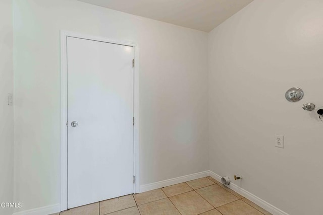 clothes washing area with light tile patterned floors, baseboards, gas dryer hookup, and laundry area